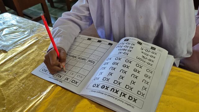 Close up of elementary girl student hands writing alphabet lesson with pencil in workbook