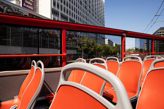 Open-top bus offers empty seats with city buildings in backdrop