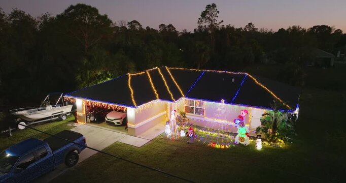 Front yard of Florida home decorated with glowing Christmas lights and ornaments, creating a festive holiday atmosphere in warm weather