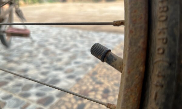 Rusty metal wheel rim and tire valve stem close-up focus on spokes and rubber tire texture