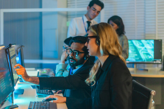Cybersecurity team monitoring security information and event management dashboard in dark war room