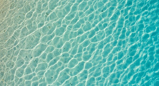 Down view of clear turquoise tropical ocean water with sunlight caustics on sandy sea floor