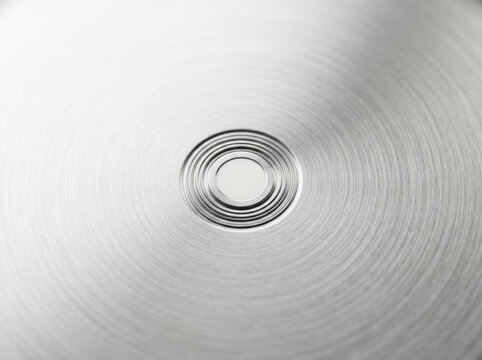 Close-up of a metallic spiral groove on a reflective surface.