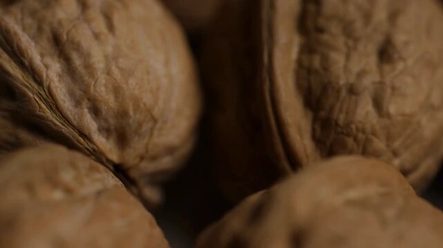 Rotating pile of raw organic walnuts in brown shells