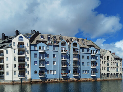 Colorful Art Nouveau architecture by the water in &Aring;lesund, Norway. Historic Scandinavian buildings near the harbor under a cloudy sky.