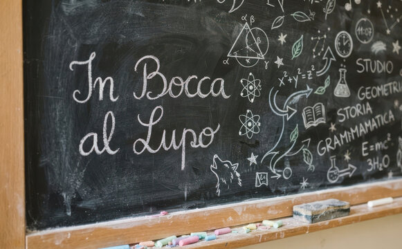 In bocca al lupo scritto con gesso su lavagna scolastica, concetto di augurio e buona fortuna per esami e studio