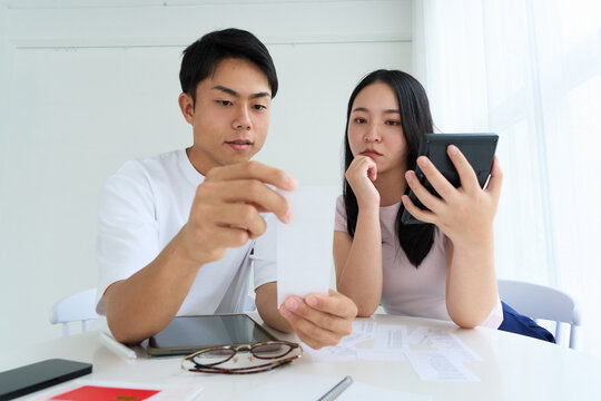 Young Japanese Man and Woman Discussing Household Finances at Table