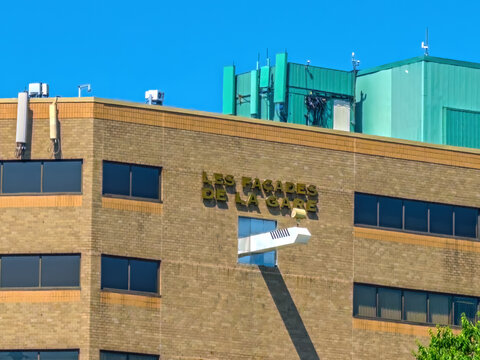 Quebec City, QC, Canada. Aug 20, 2026. Low angle view of Les Facades de la Gare brick building facade with French signage under clear sky.