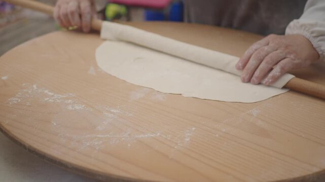 Rolling dough on a wooden surface for cooking
