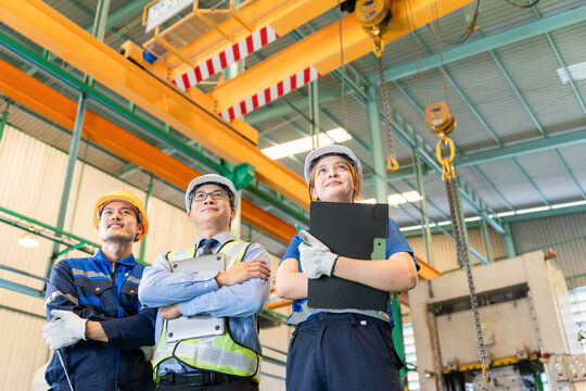 Professional Asian industrial team standing together in manufacturing factory, Successful smiling engineers and workers with arms crossed in industrial plant