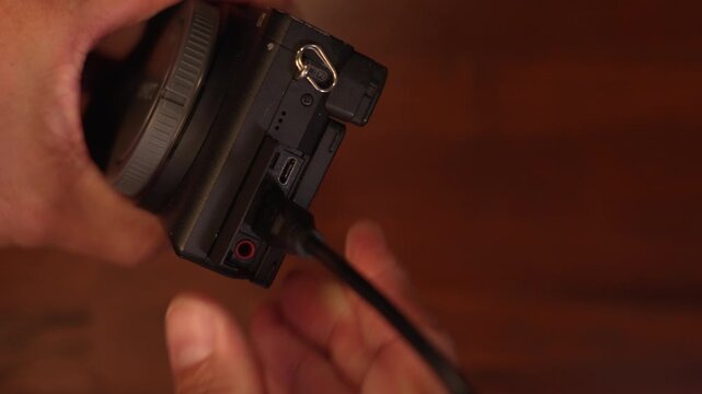 Close up shot of man hands plugging micro HDMI cable into camera body port and unplugging, digital technology and camera gear setup concept.