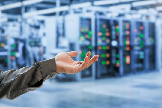 Close-up of a technician's open hand in a modern data center, with blurred server racks and glowing status lights in the background.