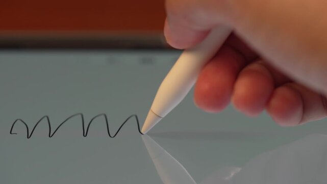 Macro shot of stylus tip drawing black line on flat digital tablet screen on wooden desk, creative graphic design workflow concept.