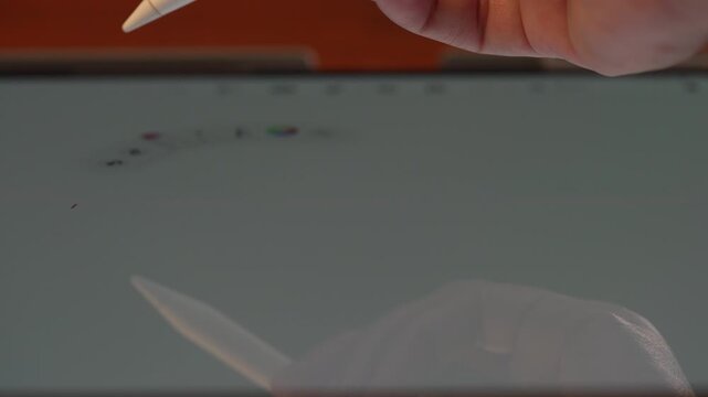 Close up of hand pressing stylus shortcut button to clear tablet screen and switching back to drawing tool, digital software workflow concept.