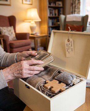 Senior person holds old photographs from a memory box at home
