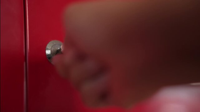 Close up of woman hand forcefully twisting key in red locker lock until it snaps off inside, breaking point concept.⁠