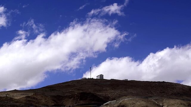 Remote scientific outpost and telecommunication tower perched on a high-altitude mountain peak under a deep blue sky in Ladakh.