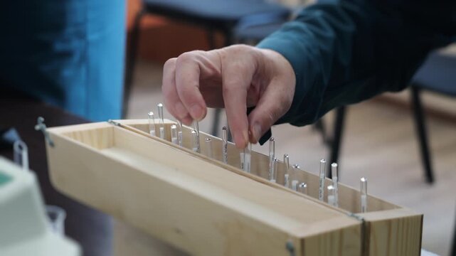 Close-up of a technician selecting a glass hydrometer from a laboratory set for measuring liquid density and specific gravity during scientific analysis.