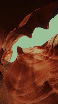 Slow upward move through a swirling sandstone slot canyon, portrait orientation