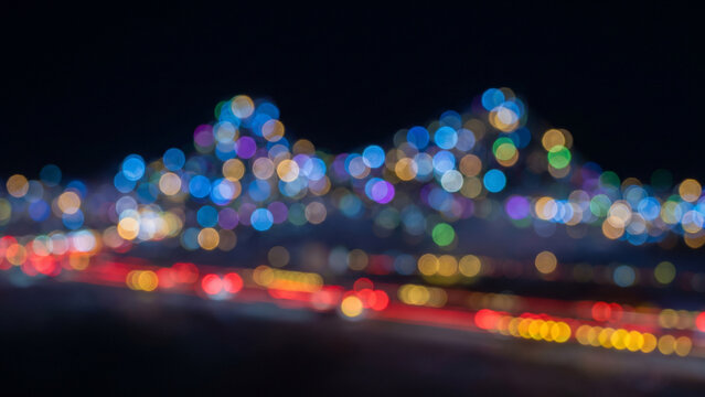漆黒の空間に赤と黄の玉ボケが光跡を描く抽象的な都市の夜景シルエット背景