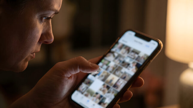 Close up of mother hand browsing smartphone photo gallery feeling overwhelmed by postpartum depression and fomo