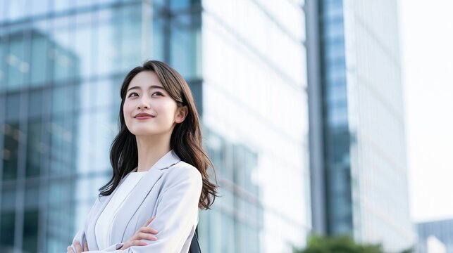 都会の景色をバックに腕を組んで穏やかに微笑む女性社員