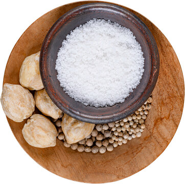 Spices coarse salt in clay bowl candlenuts white peppercorns on wooden plate isolated on transparent background