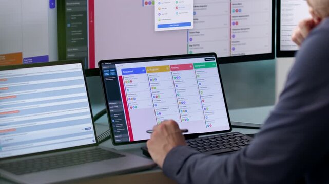 Agile Project Manager Updating Scrum Board While Using Laptop
