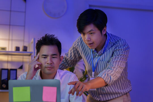 Asian business colleagues working late at night in office collaborating on laptop
