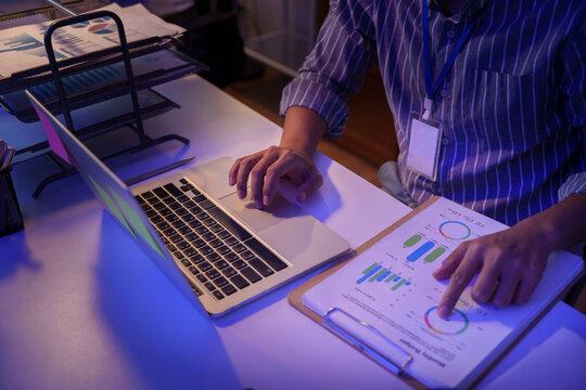 Businessman analyzing financial reports on laptop while working late