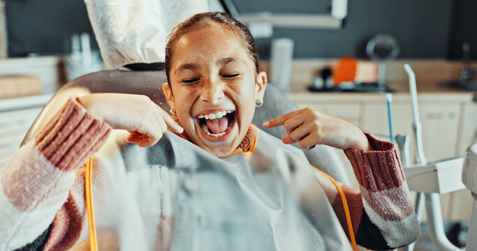 Teeth, pointing or girl with smile for dental hygiene, oral healthcare or treatment in clinic. Happy, child or kid with gum care or satisfaction for dentist cleaning, exam or appointment on chair