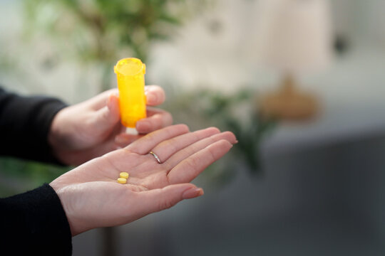 Cropped hands holding prescription pills and bottle for illness treatment and healthcare