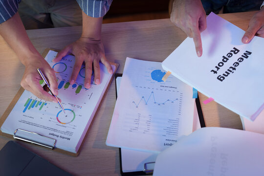 Business team analyzing financial reports on desk while working late overtime