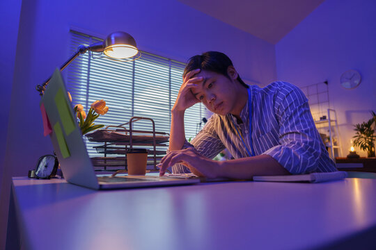 Tired Asian businessman resting head while working late at office desk
