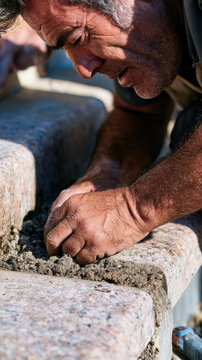 Man kneels, focused on smoothing concrete
