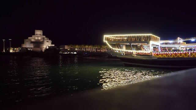Illuminated dhow boat and Museum of Islamic Art at night in Doha