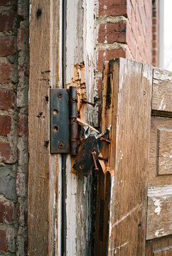 Close up of a broken exterior door hinge with a separated door panel