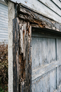 Close up of deteriorating wood trim around an exterior garage door