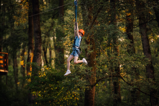 Young child ziplining through forest with safety gear