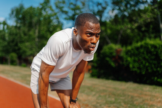 Tired male athlete catching breath after running