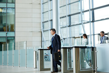 Naklejka premium Enter, walking and business man with access to office, workplace and arrive for work or career. Corporate, workers and person with scan, id card and arrival for building security, entrance and lobby