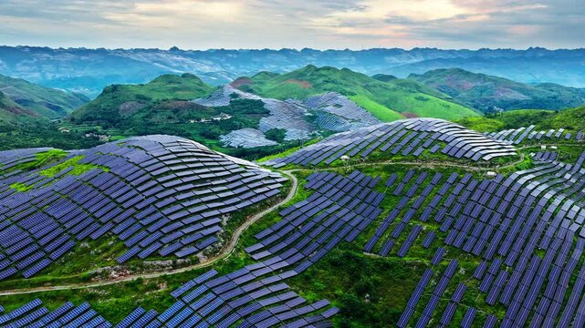 Aerial drone view of a large-scale solar farm built on rolling green hills for renewable energy in Guizhou, China.