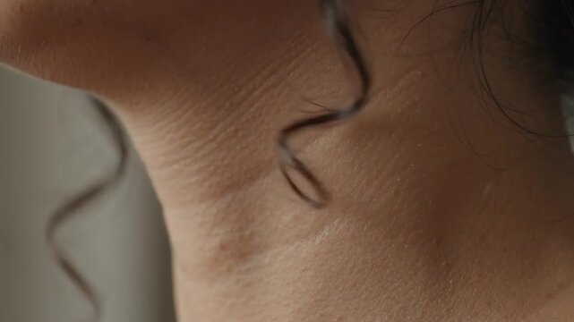 Macro Close Up of Spiral Hair Curl Bouncing Gently Along Woman Slender Neck