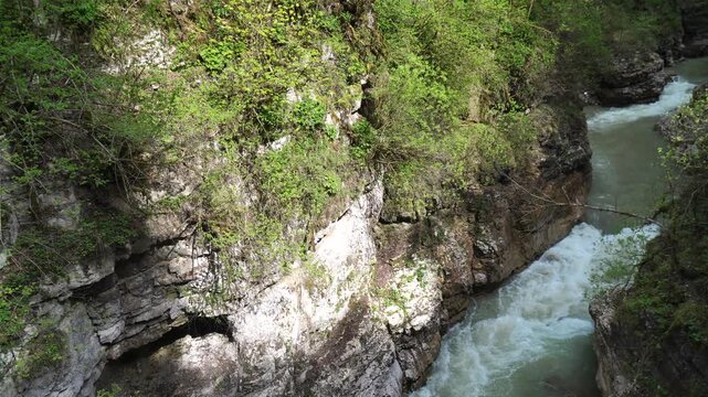 River Gorge Austria Hiking Trail - A winding river flows through a narrow gorge in the Austrian Alps, with lush green vegetation covering the surrounding rocks.