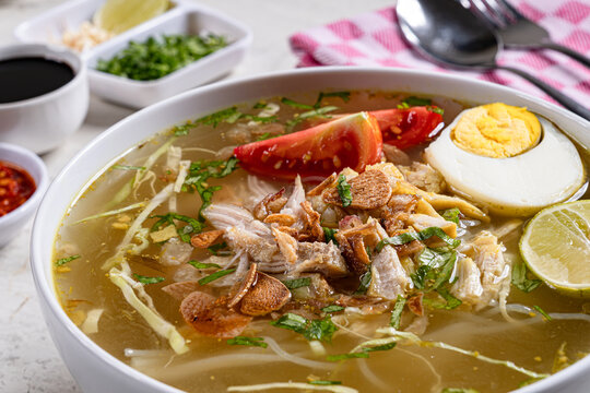 Close up authentic indonesian chicken soto soup with boiled egg fried shallots served in modern setting
