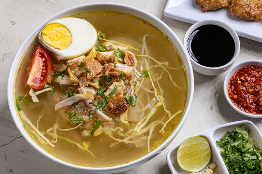 Overhead view authentic indonesian chicken soto soup with boiled egg and sambal served in a modern setting