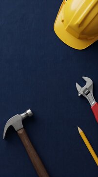 Yellow hard hat and basic carpentry tools scattered on a deep navy blue canvas background