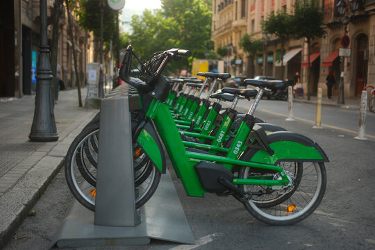 Row of bright green public electric bicycles parked at charging station on Bilbao street