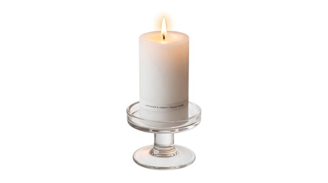 White pillar candle burning on a clear glass candlestick holder with wax candle