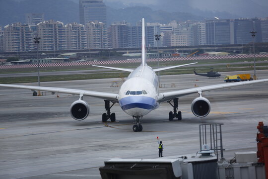 A China Airlines passenger plane is guided by a ground marshaller on the airport tarmac.